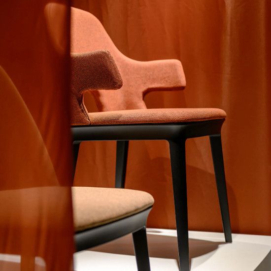 Side view of the Relay Open Back Armchair featuring burnt orange upholstery and a sleek black wooden frame.