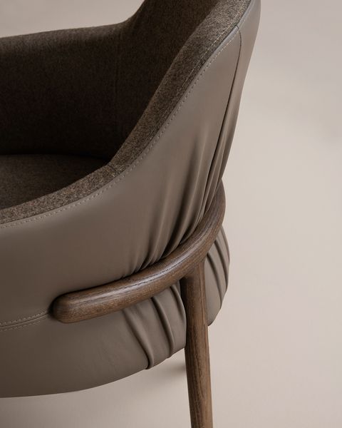 Close-up detail of a Trench Armchair showing dark wood frame accents against gathered taupe leather and wool upholstery.