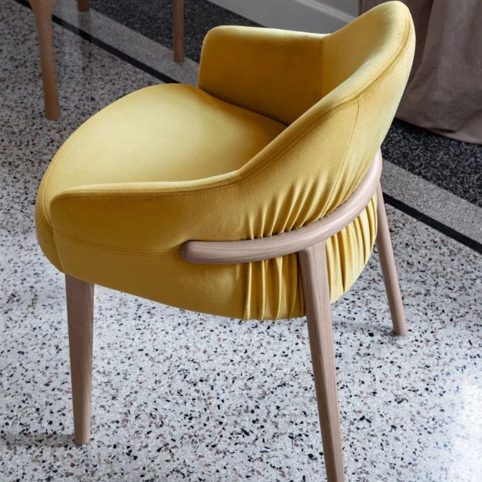 High-angle rear view of the Trench Armchair featuring vibrant yellow velvet upholstery and a light wood four-leg base.