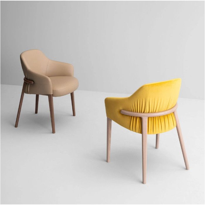 Two Trench Armchairs displayed together; one in smooth beige leather and another in pleated bright yellow velvet fabric.