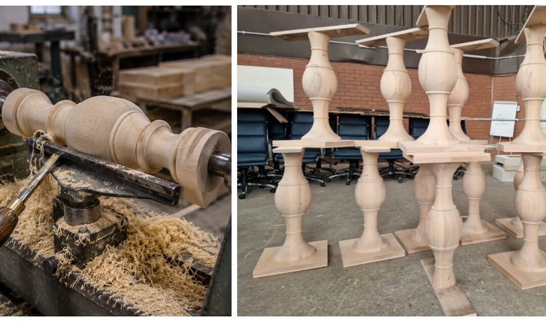 Wood lathe turning a smooth pedestal column alongside a group of finished light-colored solid wood table bases.