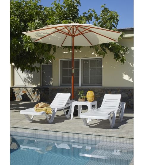 Two white Mast sun loungers poolside, positioned under a large beige patio umbrella on a sunny terrace.