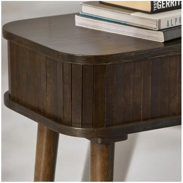 Angled view of the Ayra Console Table showing its curved corner, wooden slatted facade, and books on the top surface.