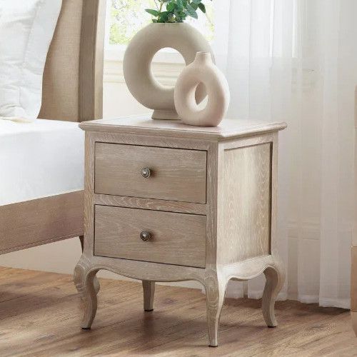 Camille bedside table featuring two drawers and sculptural legs, styled with modern ring vases in a bedroom setting.