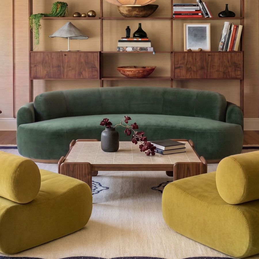 Eye-level shot of a Chess Coffee Table featuring a light tile top and wood frame, centered before a green velvet sofa.