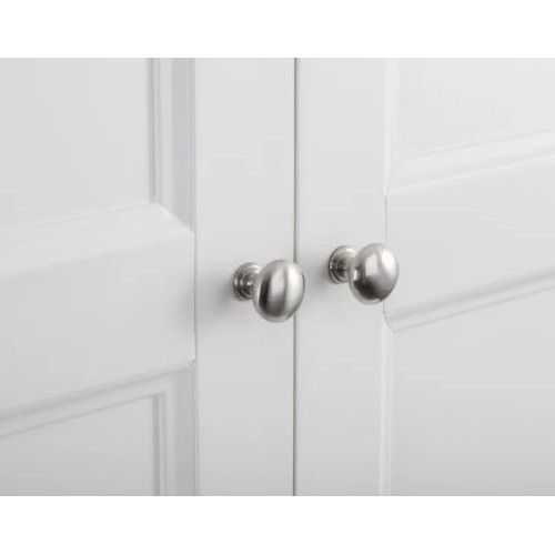 Close-up of polished silver round knobs on the white paneled doors of a Camille wooden wardrobe.