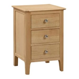 Cotswold bedside table in natural wood finish with three drawers and polished silver round knobs, studio shot.