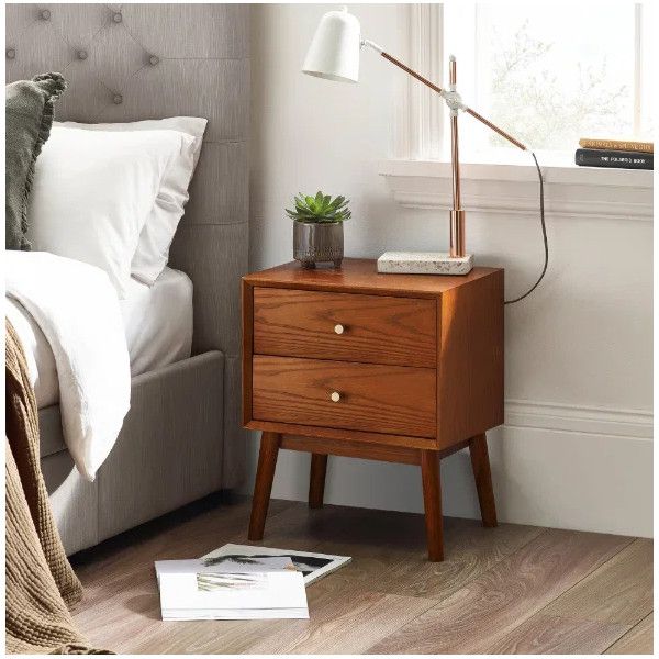 Lowry bedside table styled in a bedroom setting with a modern lamp and plant, highlighting its rich wood grain finish.