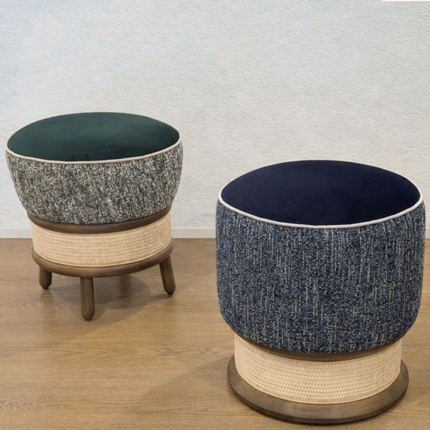 Two Miko Low Stools with dark circular upholstered tops, blue-toned textured sides, and woven rattan bases on wood floors.