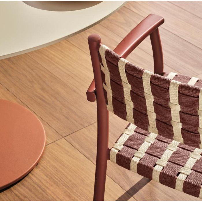 Close-up view of a Nuova Guinea armchair featuring a terracotta frame and a woven checkered seat on wood flooring.