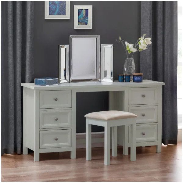 Maine Desk Table styled as a vanity with a matching upholstered stool, mirror, and decor against a dark grey wall.