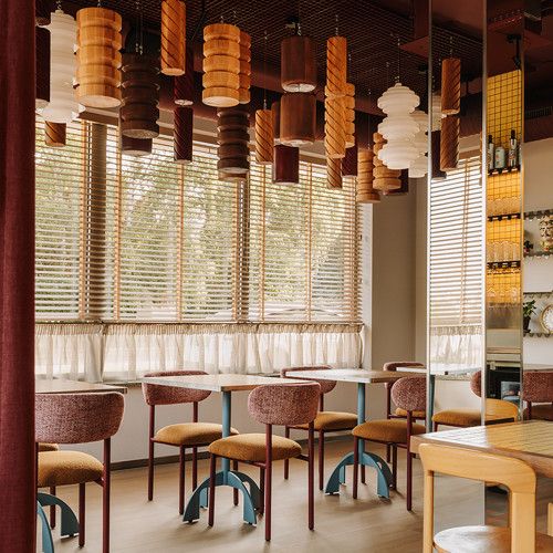 Wide shot of blue Noru dining table bases with arched legs set in a restaurant with warm ambient lighting.
