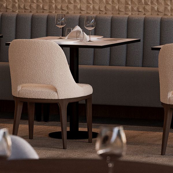 Axis Side Chair in textured cream fabric with wrap-around back and sculpted wood legs, dining setup.