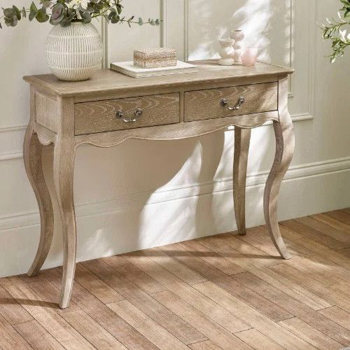 Camille Console Table in light oak with two drawers, styled in a bright room with sunlight.
