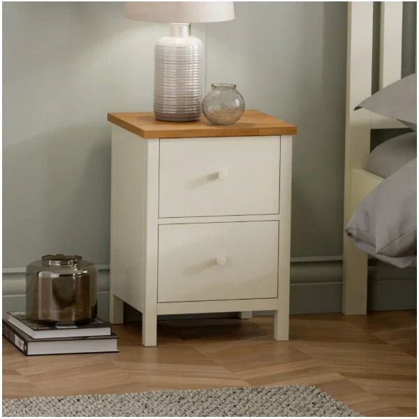 Ivory and oak Coxmoor 2 draw bedside styled in a bedroom setting with a table lamp and books.