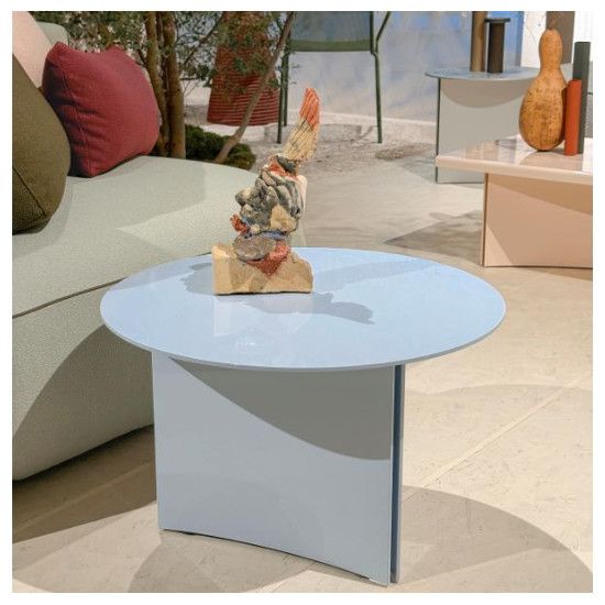 Glossy sky-blue Estratto round coffee table shown at an angle, displaying its sleek metal frame in a decorated interior.