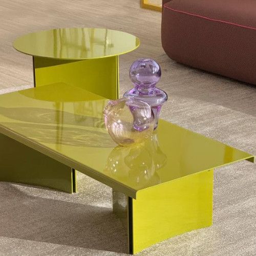 Glossy chartreuse Estratto metal tables styled in a lounge setting with decorative glass ornaments.
