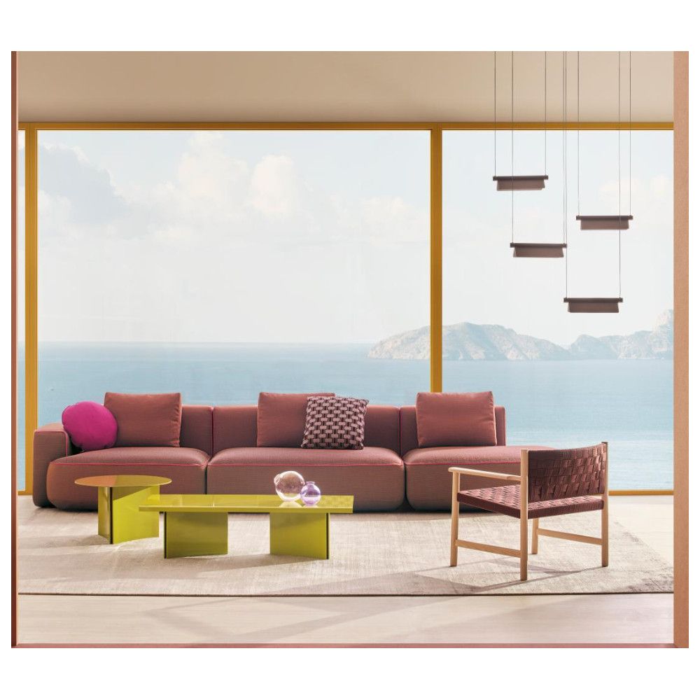 Bright olive Estratto coffee tables arranged as a set in a modern seaside lounge with a large sofa and ocean views.