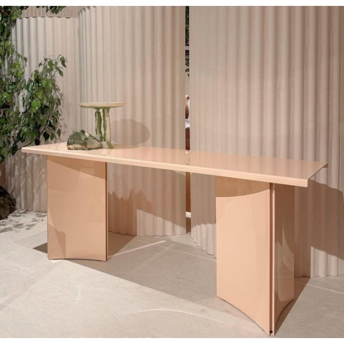 Estratto dining table in a soft peach finish, featuring a wide rectangular top and dual curved panel base supports.