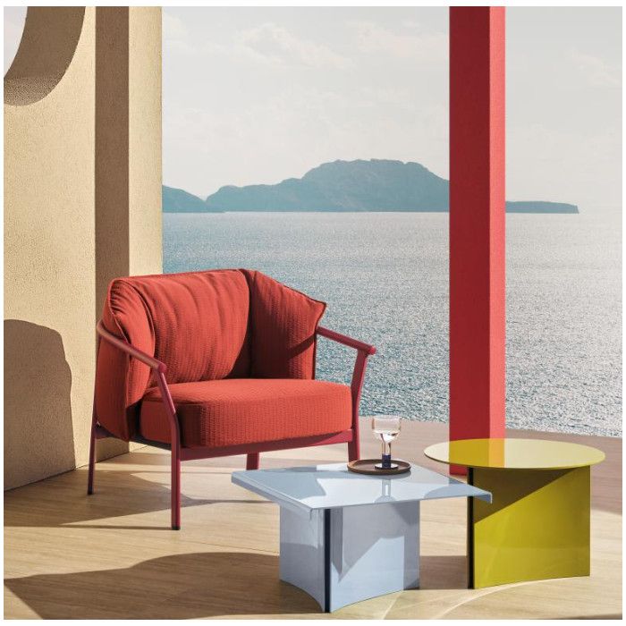 Estratto round coffee table in vibrant lime yellow paired with a square blue table on a sunny sea-view terrace.