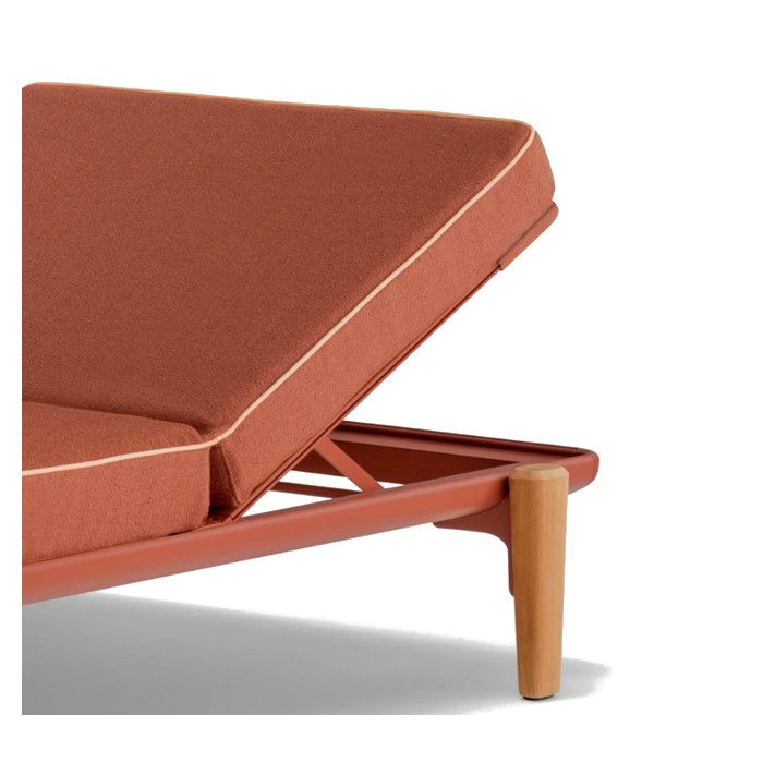 Close-up of the Fibra Sun Lounger showing the rust-colored metal frame, textured cushion, and sturdy wooden leg.