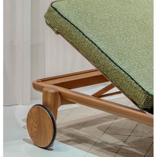 Fibra W Sun Lounger featuring a textured green cushion, light wood frame, and circular wheel in a close-up angle.
