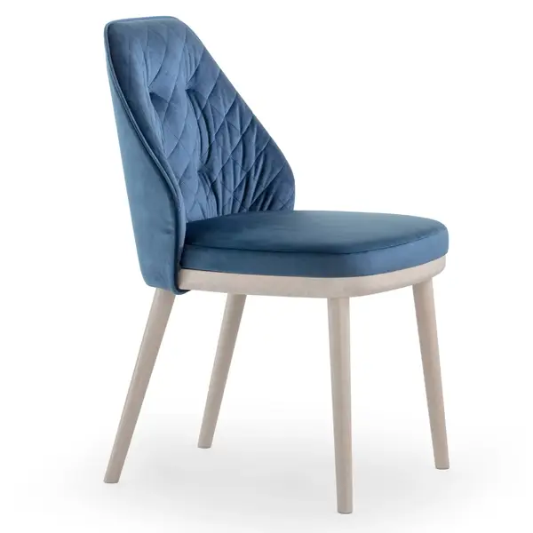 Profile shot of Iris Side Chair featuring blue quilted velvet upholstery and light wooden legs on white backdrop.