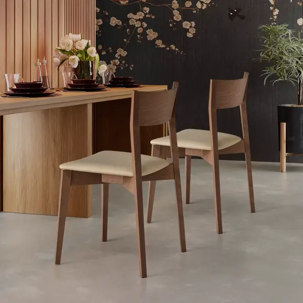 Two Miss Side Chairs featuring dark wooden frames and cream seats, arranged near a dining table in a modern interior.