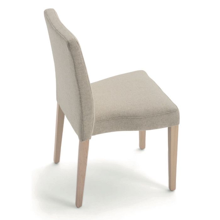 Rear three-quarter view of the Miss Stacking Side Chair featuring light neutral upholstery and natural wooden legs.