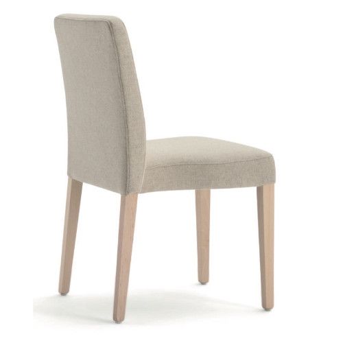 Profile angle of the Miss Stacking Side Chair showing smooth cream fabric upholstery and light wooden legs.