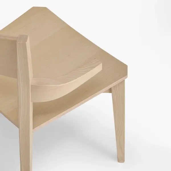 Close-up of the Miss W Armchair showing the curved wooden backrest and grain detail from a high-angle side view.