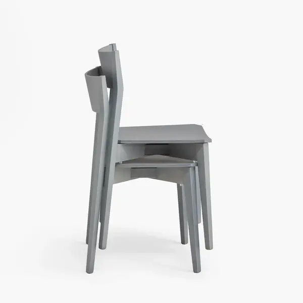 Side view of two stacked Miss W wooden chairs in light grey, showcasing their streamlined profile and space-saving design.