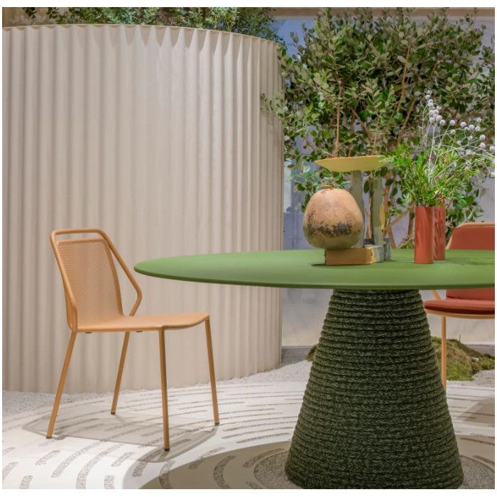 Philia Mesh Side Chair in warm beige positioned beside a modern green circular dining table in a curated interior space.