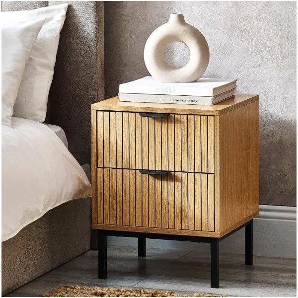 Sia bedside table styled in a modern bedroom with a decorative vase and books placed on top of its slatted drawer unit.