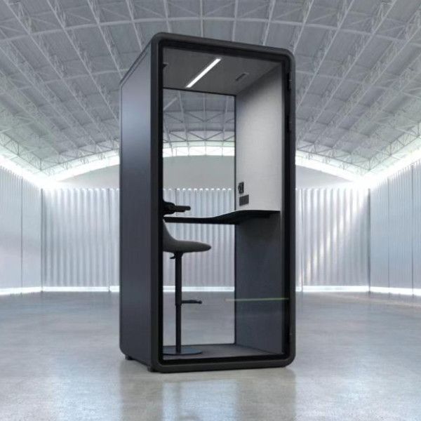 Isla Side Chair: tall black upholstered seat on wood frame, front angle in spacious industrial hall.
